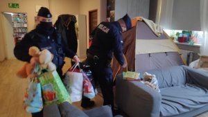 zdjęcie kolorowe: policjanci wnoszący pakunki do sali zabaw