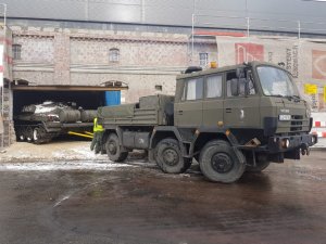 zdjęcie kolorowe: samochód ciężarowy i czołg w chwili umieszczania czołgu w budynku