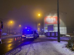 zdjęcie kolorowe: policyjny radiowóz zaparkowany przy drodze obok kamienicy