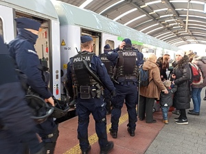 zdjęcie kolorowe: policjanci katowickiego oddziału prewencji na stacji kolejowej przy pociągu z uchodźcami