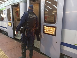 zdjęcie kolorowe: policjant katowickiego oddziału prewencji przy pociągu, którym podróżują uchodźcy