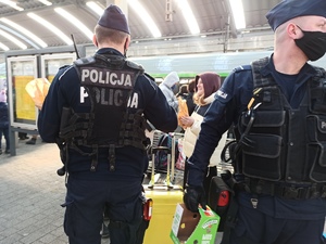 zdjęcie kolorowe: policjanci katowickiego oddziału prewencji rozdający jedzenie uchodźcom na katowickim dworcu