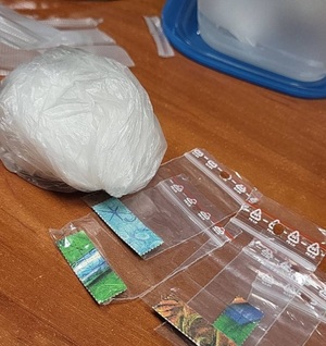 zdjęcie kolorowe: zabezpieczone przez policyjnych wywiadowców narkotyki: worek z amfetamina i listki LSD