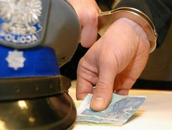 zdjęcie kolorowe: policyjna czapka i wsuwane pod nią banknoty