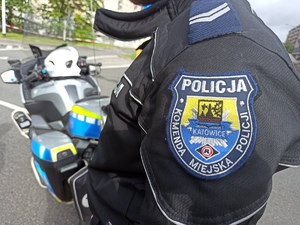 zdjęci kolorowe: policjant katowickiej drogówki stojący przy motorze służbowym