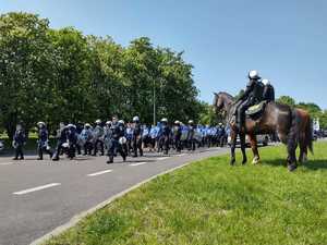 zdjęcie kolorowe: policyjne konie i policjanci zabezpieczający przemarsz kibiców