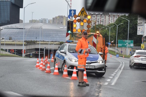 3 - zdjęcie kolorowe: ekipa rozkładająca bariery na trasie w rejonie zaparkowanego radiowozu