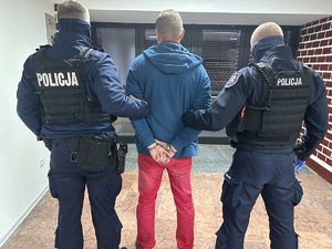zdjęcie kolorowe: dwóch umundurowanych policjantów z zatrzymanym mężczyzną, który miał narkotyki
