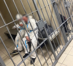 zdjęcie kolorowe: dwóch zatrzymanych mężczyzn osadzonych w policyjnej celi