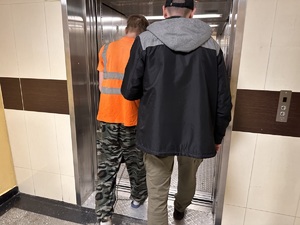 zdjęcie kolorowe: policjant wchodzący z zatrzymanym do windy