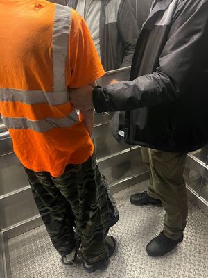 zdjęcie kolorowe: policjant i zatrzymany stoją w windzie