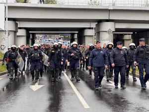 zdjęcie kolorowe: policjanci oddziału prewencji zabezpieczający przemarsz kibiców na mecz piłki nożnej rozegrany pomiędzy drużynami GKS-u Katowice i Pogoni Szczecin