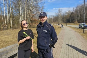 Na zdjęciu policjant wręczający kwiaty kobiecie