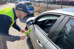 Na zdjęciu policjant wręczający kwiaty kobiecie