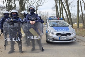 Na zdjęciu policjanci z tarczami przy radiowozie