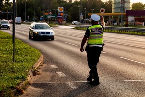 Na zdjęciu policjant zatrzymujący pojazd