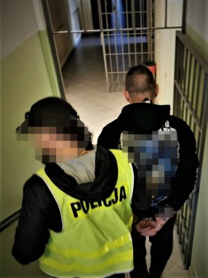 na zdjęciu widać dwóch mężczyzn, którzy schodzą ze schodów w budynku aresztu. Jeden z nich to policjant kryminalny, drugi to zatrzymany
