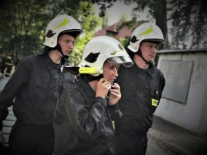 troje strażaków - ochotników ubiera na głowę kaski
