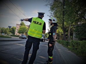 policjant drogówki stoi przy drodze i udziela rad słuchaczowi jak kierować ruchem