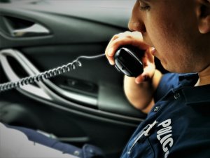 policjant drogówki trzyma w ręce częśc radiotelefonu i prowadzi korespondecję