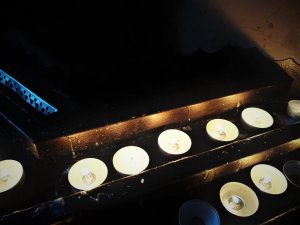 ustawione w szeregu palące się świece w kościele