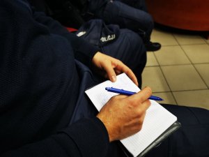 policjant dokonuje wpisu do notatnika służbowego