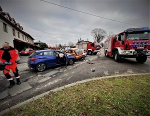 skrzyżowanie ulic w Mikołowie, trzy rozbite samochody, prowadzący akcję strażacy, w tle budynki