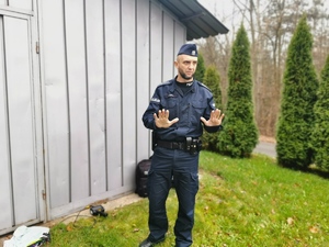 na zdjęciu policjant, który dłońmi pokazuje, że pakunek jest bezpieczny