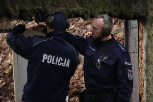 dwaj policjanci przybijają papierowe tarcze do belki