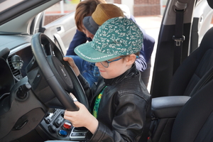 mały chłopiec siedzi za kierownicą policyjnego radiowozu