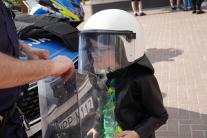 mały chłopiec pozuje do zdjęcia mając na sobie kask ochronny policjanta prewencji