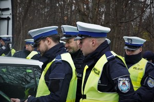policjanci drogówki w odblaskowych kamizelkach podczas kontroli samochodu