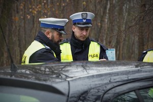 dwaj policjanci drogówki stoją przy samochodzie
