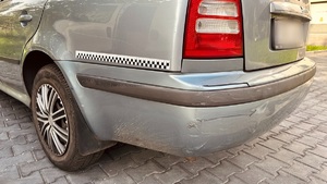 zdjęcie przedstawia zbliżenie na uszkodzony zderzak zaparkowanej skody