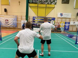 zdjęcie przedstawia zawodników w trakcie meczu badmintona na hali sportowej