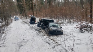 zdjęcie przedstawia trzy pojazdy stojące w lesie. w tle radiowóz
