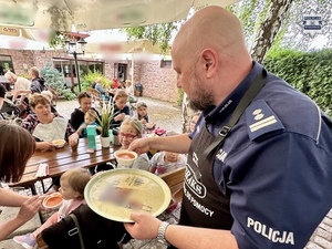 zdjęcie przedstawia policjanta podającego posiłki dzieciom