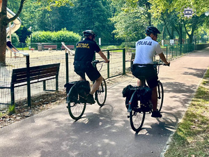zdjęcie przedstawia policjanta i strażnika miejskiego na rowerach.