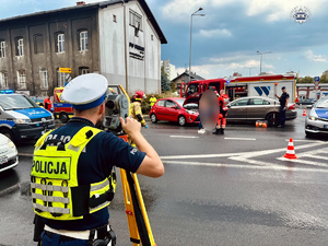 zdjęcie przedstawia policjanta wykonującego pomiary na miejscu wypadku