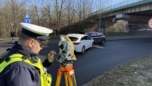 zdjęcie przedstawia policjanta dokonującego pomiarów na miejscu kolizji