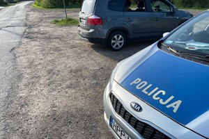 zdjęcie przedstawia samochód zatrzymanego stojący obok radiowozu