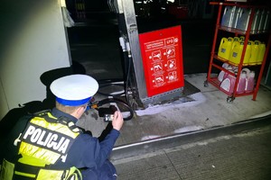 zdjęcie przedstawia policjanta dokonującego oględzin dystrybutora