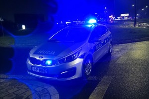 zdjęcie przedstawia radiowóz, który stoi na ulicy, w tle działania służb