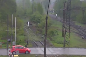zdjęcie przedstawia samochód przejeżdżający przez przejazd kolejowy