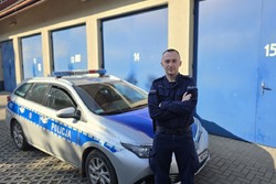 zdjęcie przedstawia policjanta przy radiowozie