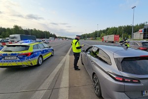 zdjęcie przedstawia policjanta w trakcie kontroli trzeźwości kierującego