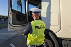 zdjęcie przedstawia policjanta przy samochodzie ciężarowym