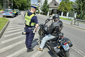 zdjęcie przedstawia policjanta w trakcie kontroli motocyklisty