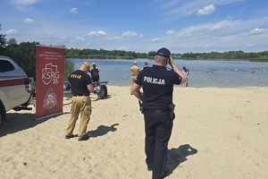 zdjęcie przedstawia policjanta i strażaków obserwujących wodę
