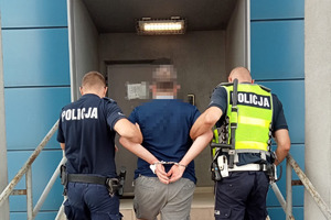 zdjęcie przedstawia policjantów doprowadzających zatrzymanego